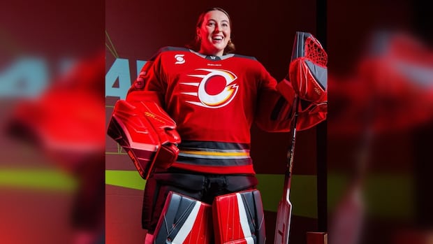 A female hockey goalie in a red uniform