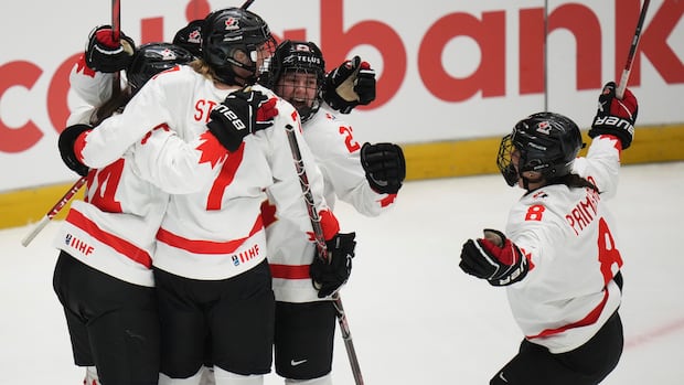 Members of the Canadian women's hockey team celebrate on the ice.
