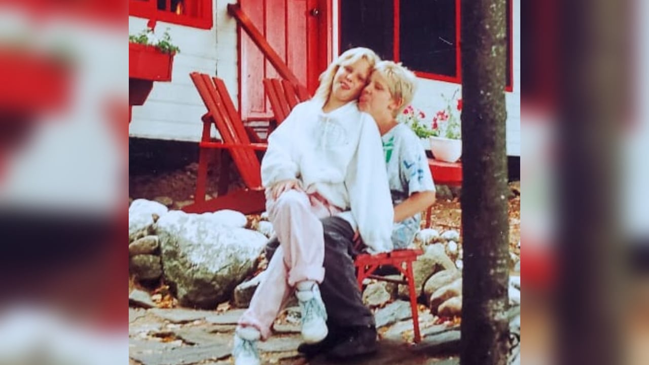 A girl sits on top of a boy's lap and they are making silly faces.