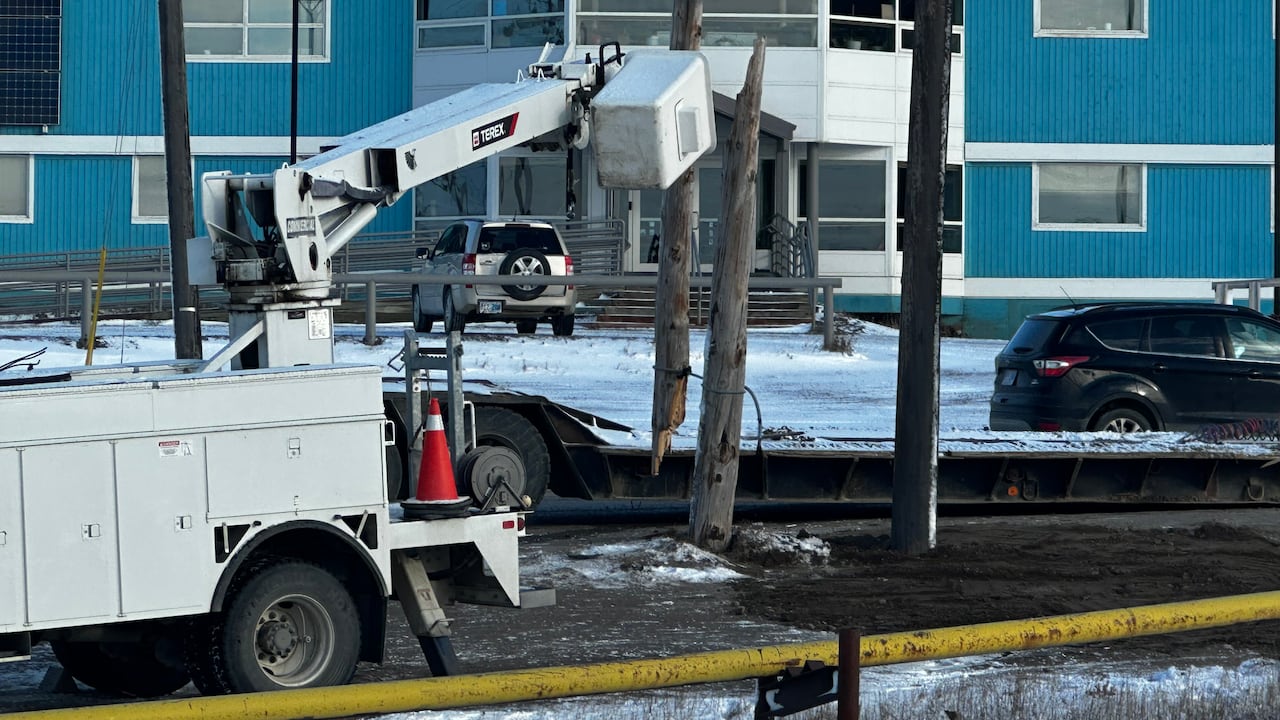 A machine near a broken power pole in front of a blue building