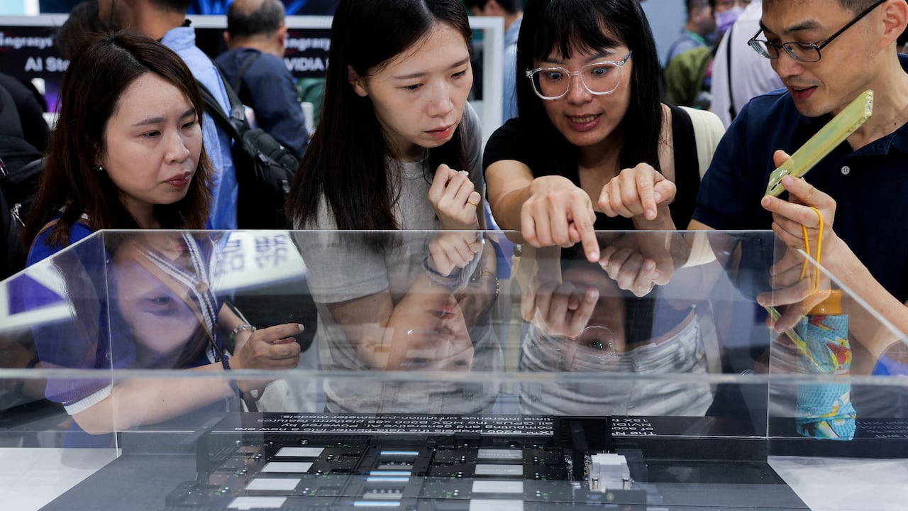 A group of people study computer equipment on display.