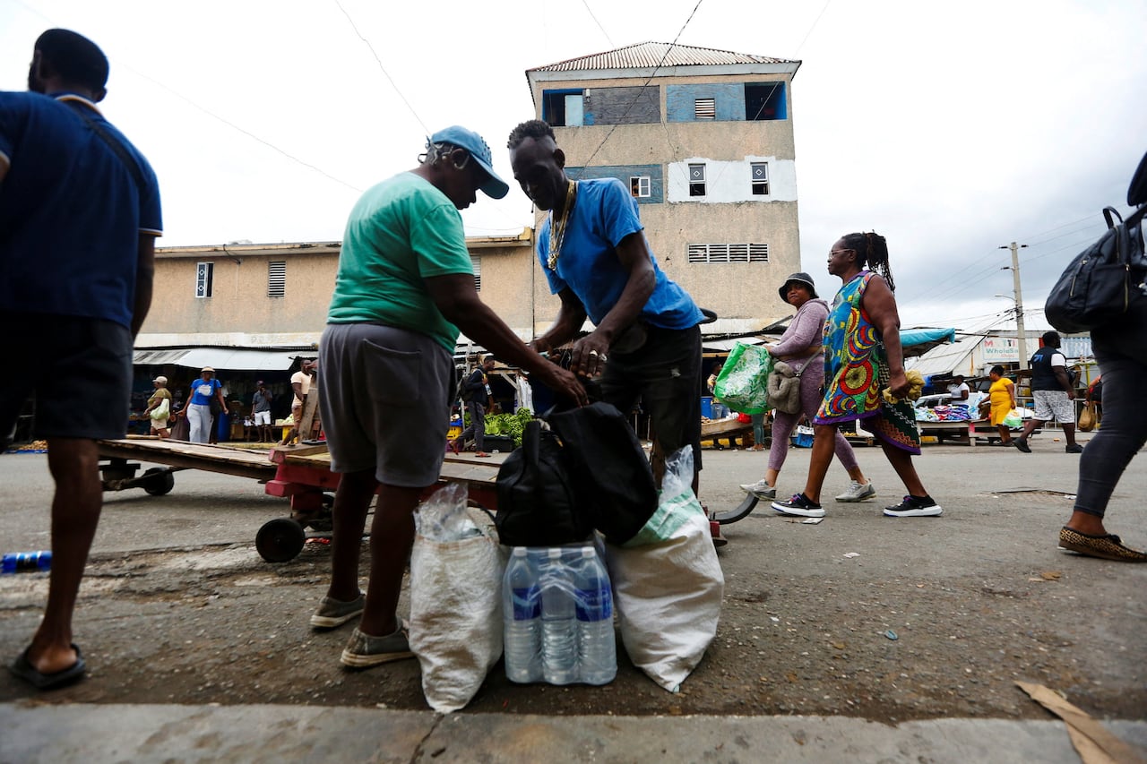 People are seen with their groceries on the side of a street.