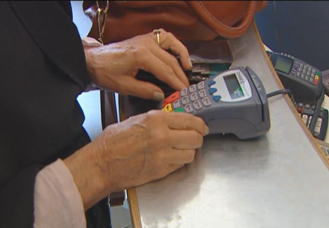 A man touches a payment machine with a credit card.