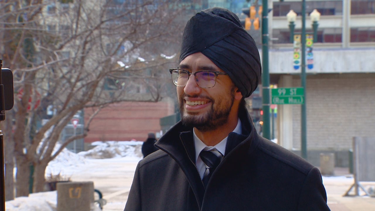 man smiles at camera, outdoors when it's snowy. 