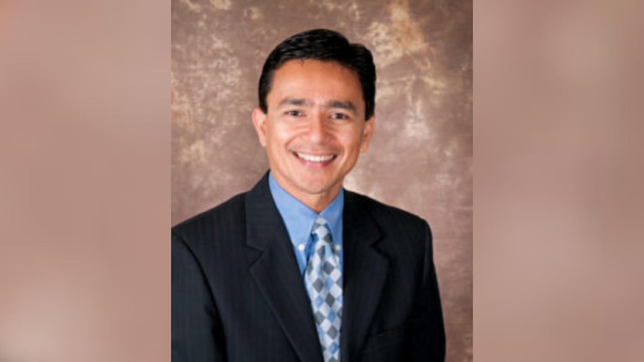 A young antheral with a caput of acheronian hairsbreadth smiles wide astatine the camera.