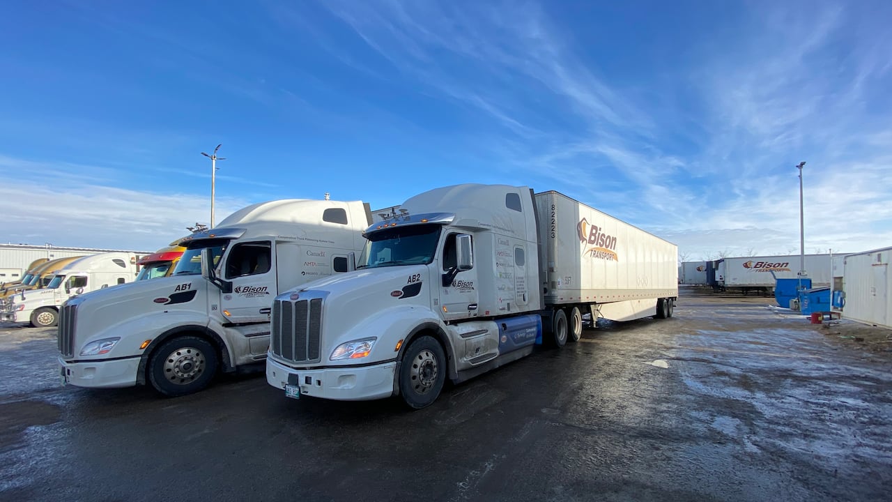 Two white trucks sit in a parking lot.