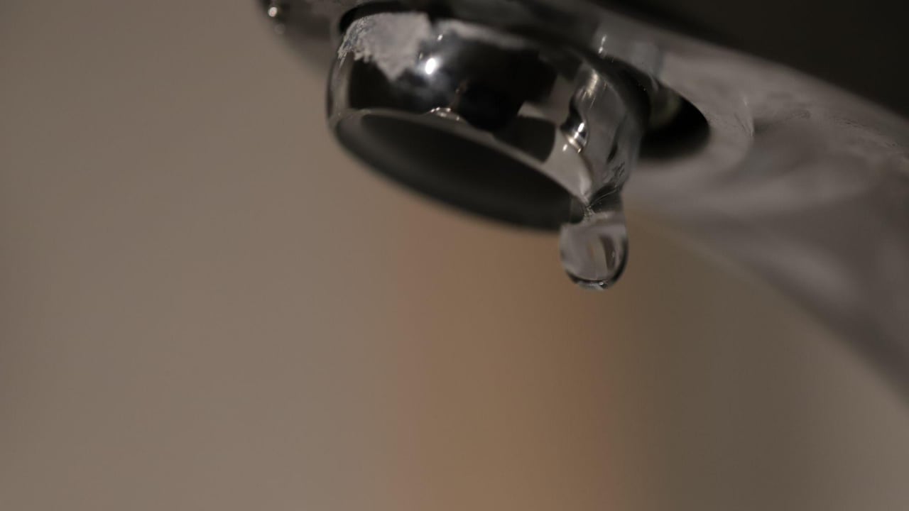 a driblet of h2o drips from a tap.