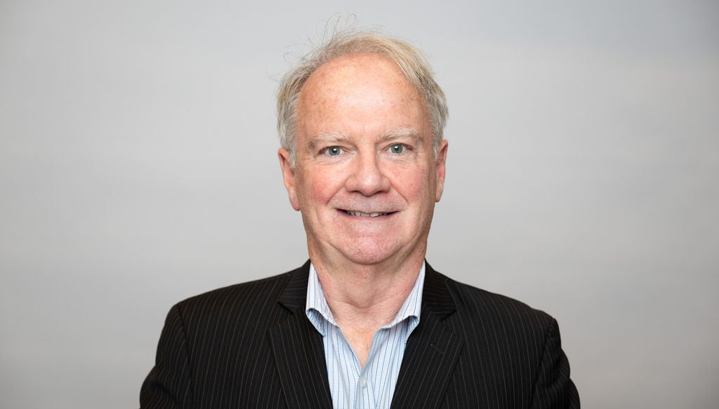 A man smiles, looking straight ahead.