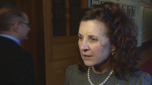 B.C. Conservative MLA Dallas Brodie responds to criticism about a social media post about the former Kamloops Indian Residential School. A woman in a grey shirt and curly hair stands in the legislature hallways.