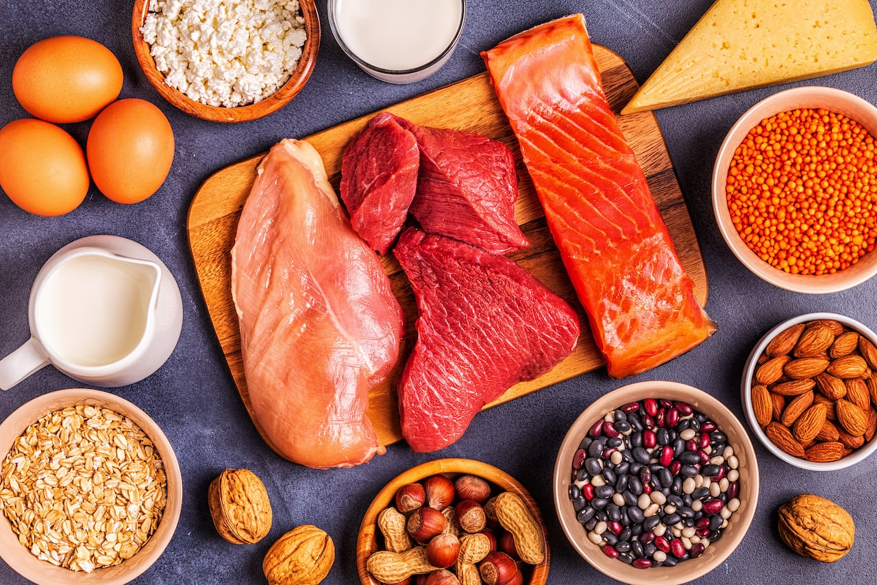 Protein-rich foods such as meat, nuts, cheeses and eggs on a table and board.