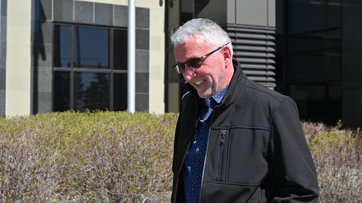 A smiling man in a black coat. 