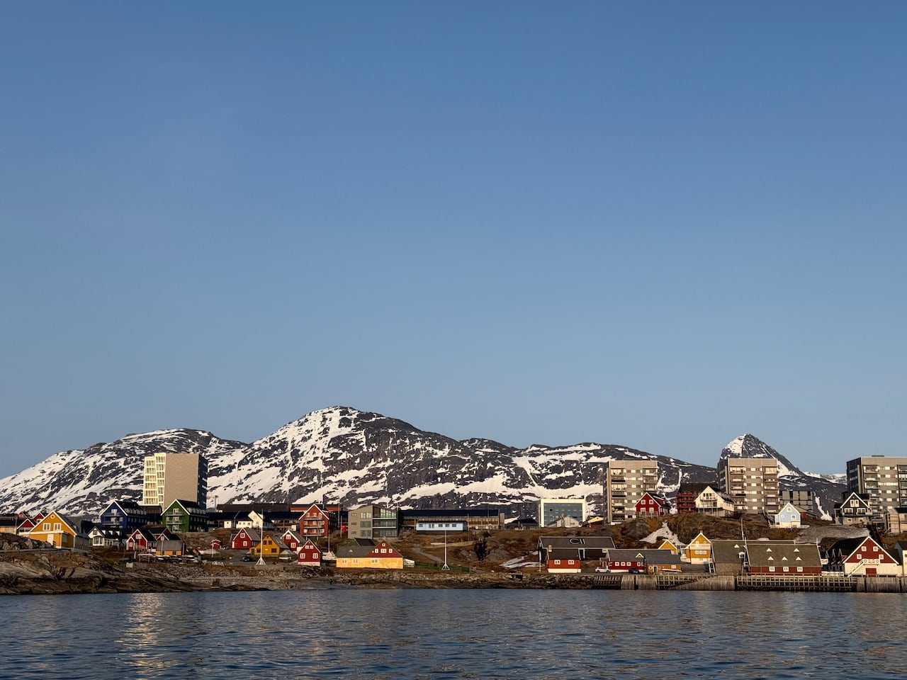 An array of colourful houses. Behind them is a mountain