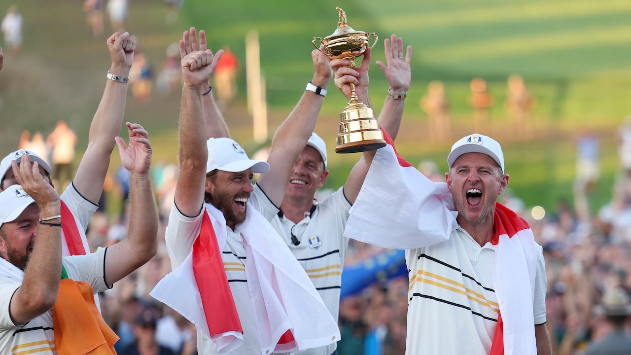 A radical  of golfers draped successful  flags clasp  a trophy.