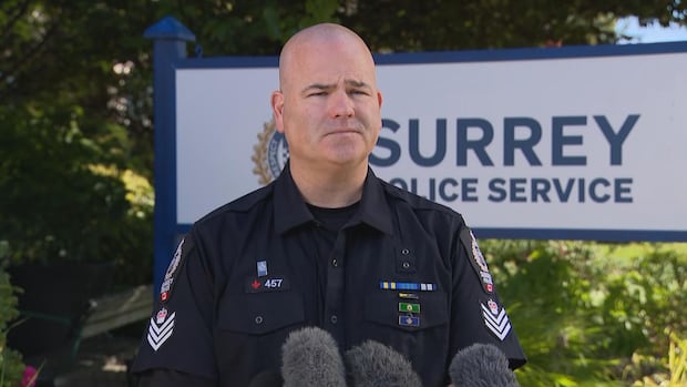Surrey Police Service Staff Sgt. Lindsey Houghton tells reporters on Oct. 6, 2025, that three men have been charged in what is believed to be an extortion-related shooting. A police officer stands in front of a Surrey police sign