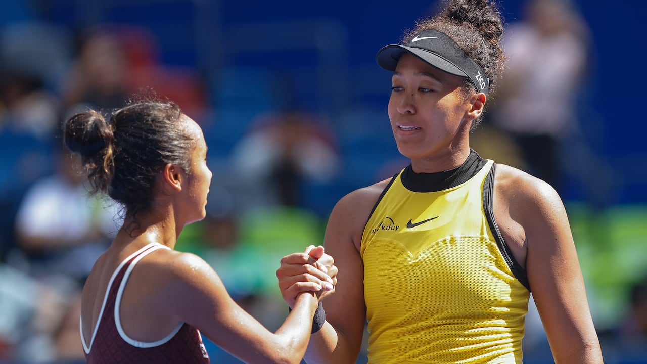 Two women's tennis players shingle hands.