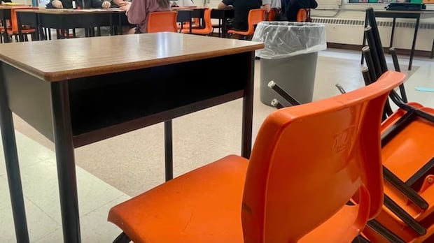 An empty student desk and chair in a classroom.