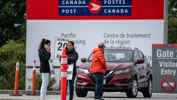 Canada Post workers are pictured on strike at the Canada Post processing centre in Richmond, B.C., on Friday, Sept. 26, 2025. Postal workers wearing signs during a strike outside a sorting facility.