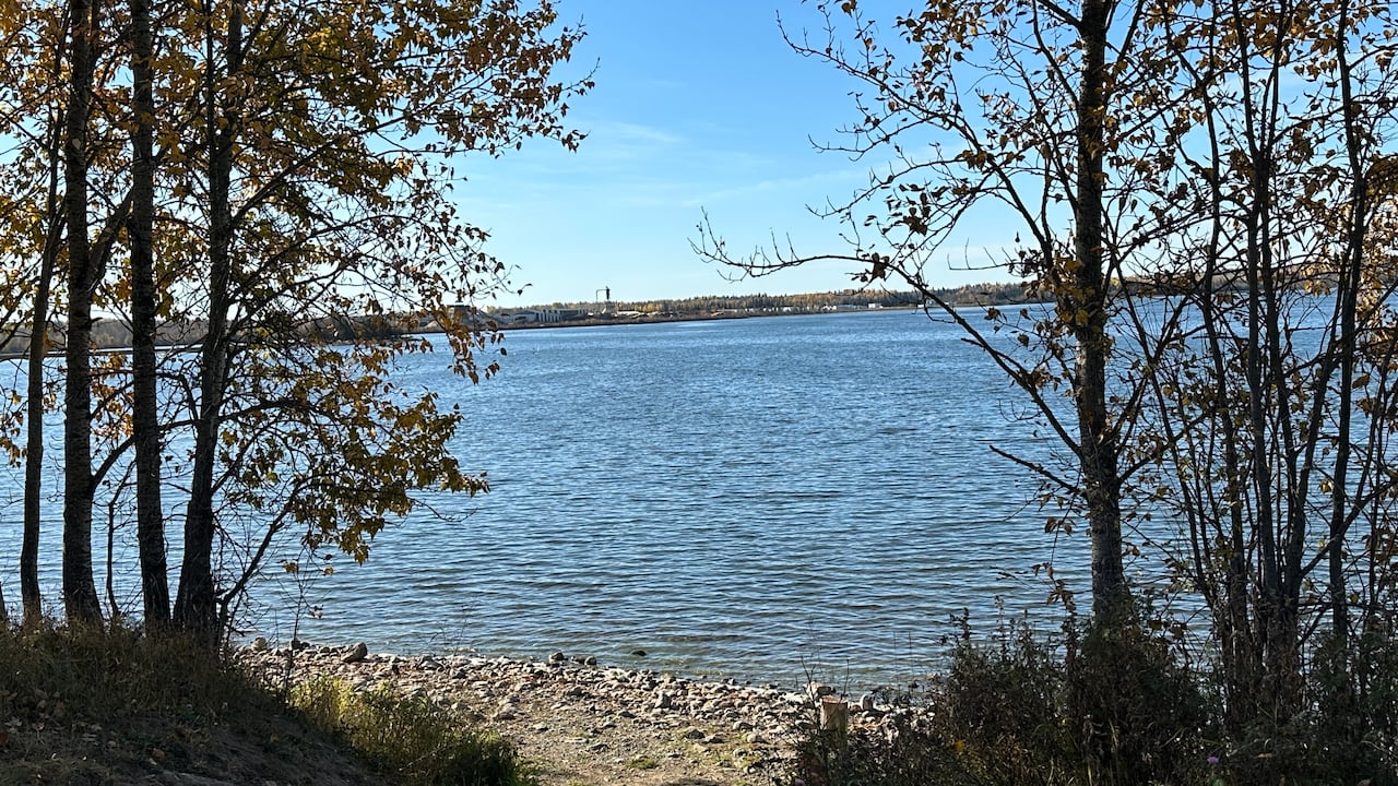 Piękne błękitne jezioro z kilkoma skałami na brzegu i tartakiem na przeciwległym brzegu