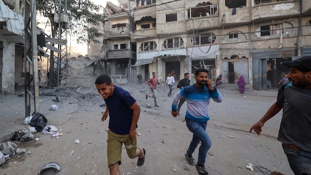 People run for cover in a war-torn street.