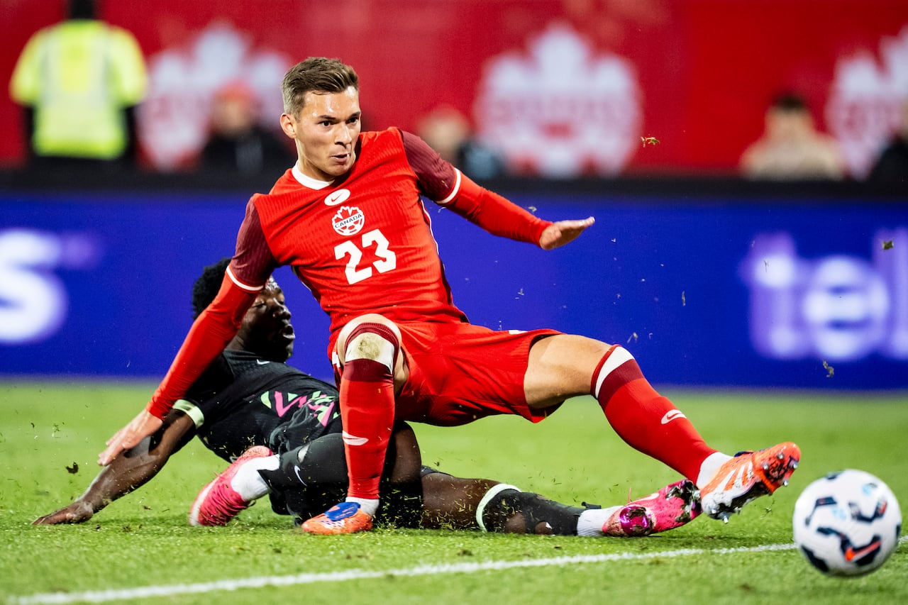A Canadian soccer player is tackled by an Australian player during a match.