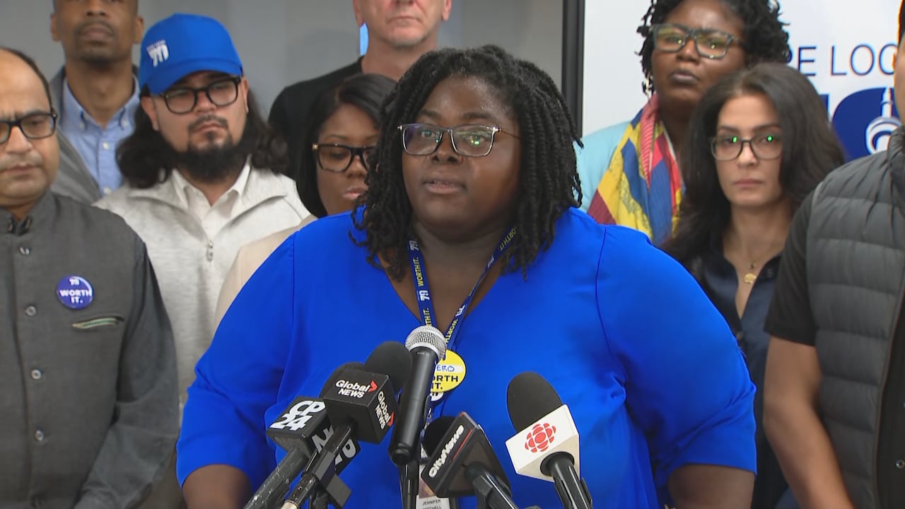 Woman speaks into a microphone portion wearing a bluish shirt.