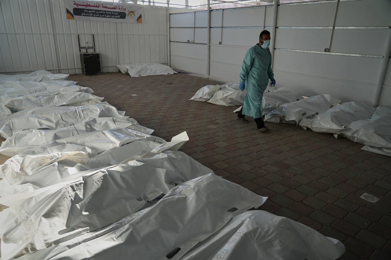 Bodies lie in plastic bags on the floor.