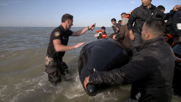 An image from video of police officers in water beside a crowded boat.
