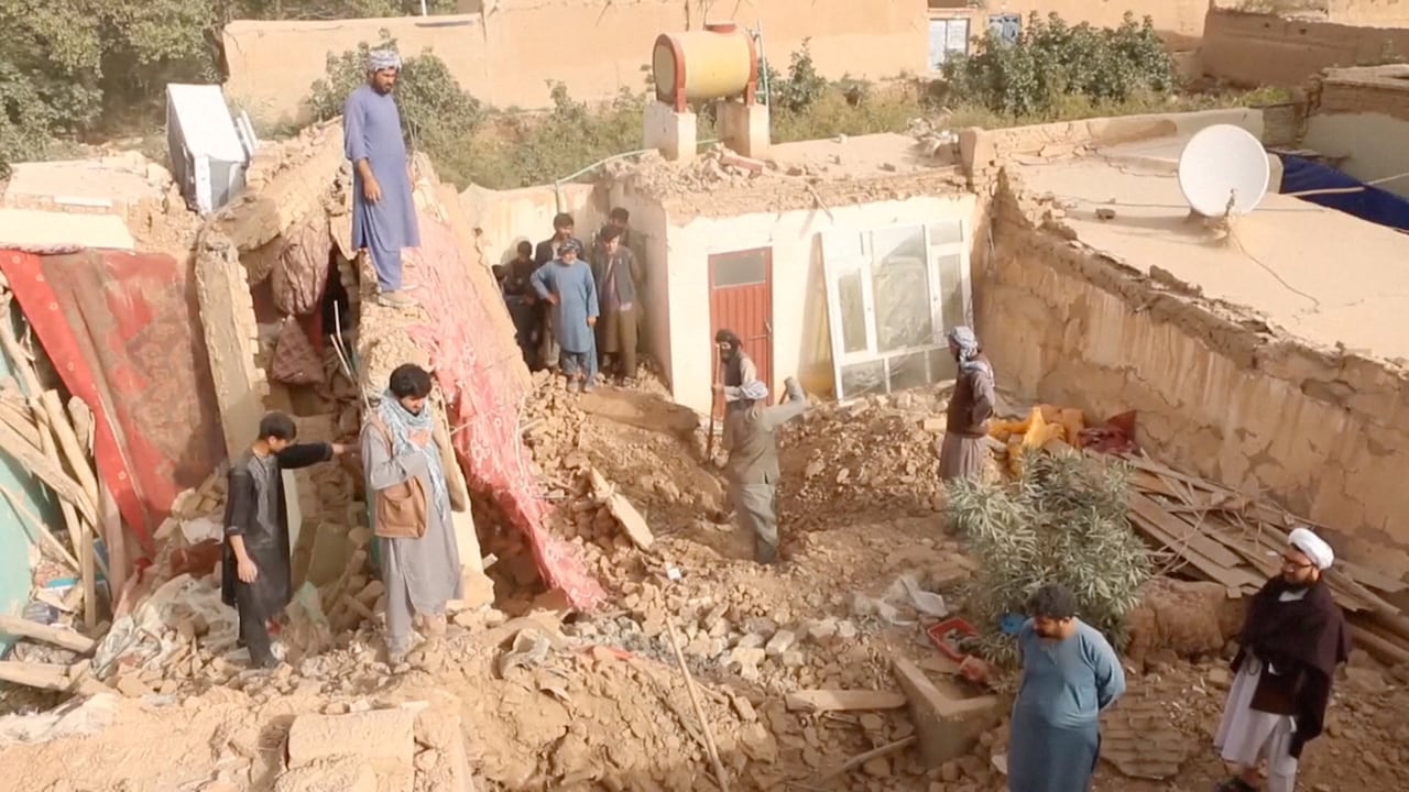 A group of men and boys dig through the rubble of a home.