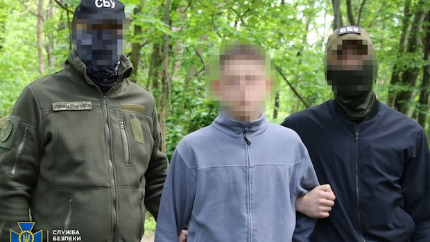 Two soldiers bracket a shorter man. All of their faces are blurred