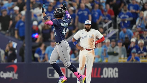 A baseball player raises his hands in celebration as he rounds the bases.