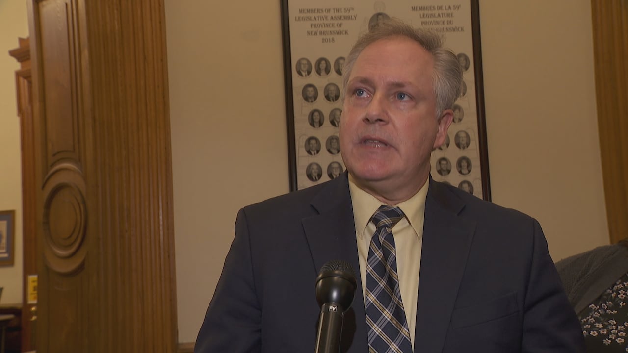 Man in suit speaks into microphones.