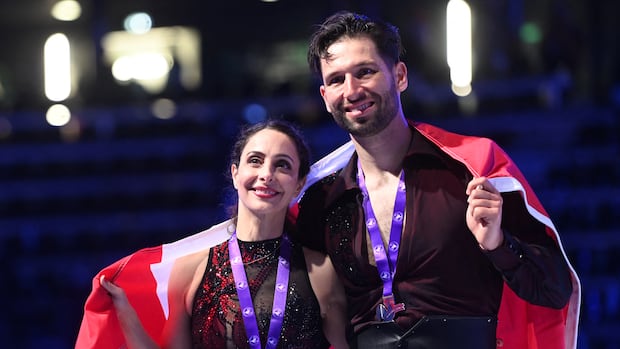Canada's Deanna Stellato-Dudek (L) and Maxime Deschamps react after their second place in the pairs' free programme of the ISU 2025 figure skating French Grand Prix in Angers, western France, on October 18, 2025. (Photo by JEAN-FRANCOIS MONIER / AFP) (Photo by JEAN-FRANCOIS MONIER/AFP via Getty Images) Two figure skaters pose with their medals and a Canada flag.