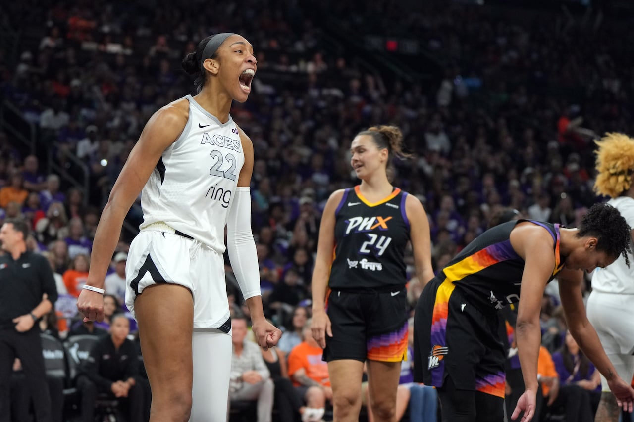 A basketball player celebrates as opposing players look on.