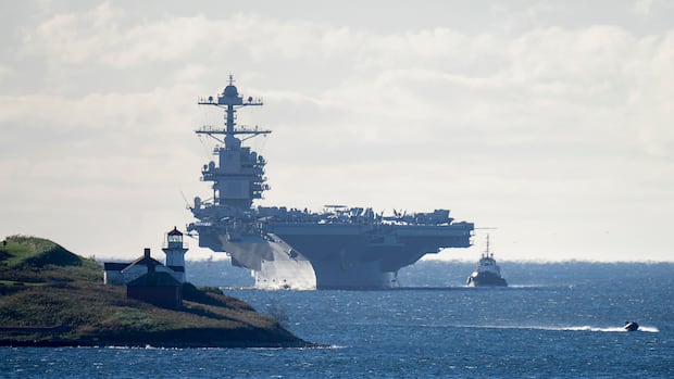 The USS Gerald R. Ford, one of the world's largest aircraft carriers, arrives in Halifax on Friday, Oct. 28, 2022. The United States Navy's most advanced aircraft carrier is on its first deployment, five years after it was commissioned into service. THE CANADIAN PRESS/Andrew Vaughan A large aircraft carrier sails near a coastline.