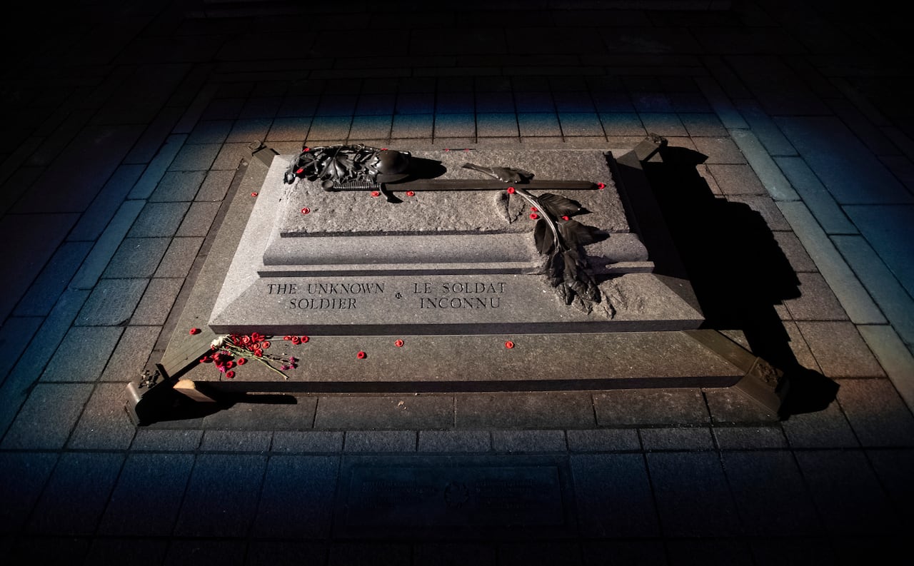 A light shines on a memorial grave marked "The Unkown Soldier."