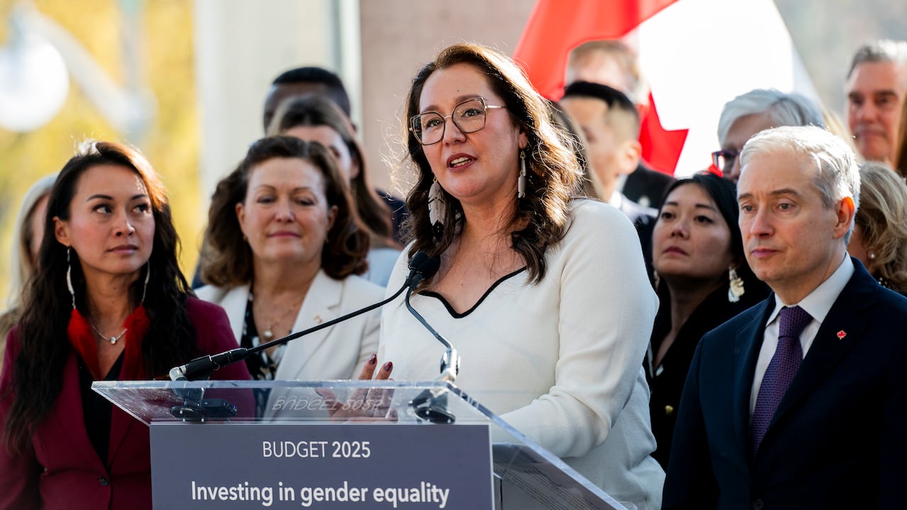 Mandy Gull-Masty speaks into a microphone flanked by different   ministers with a Canadian emblem  successful  the backgroun.