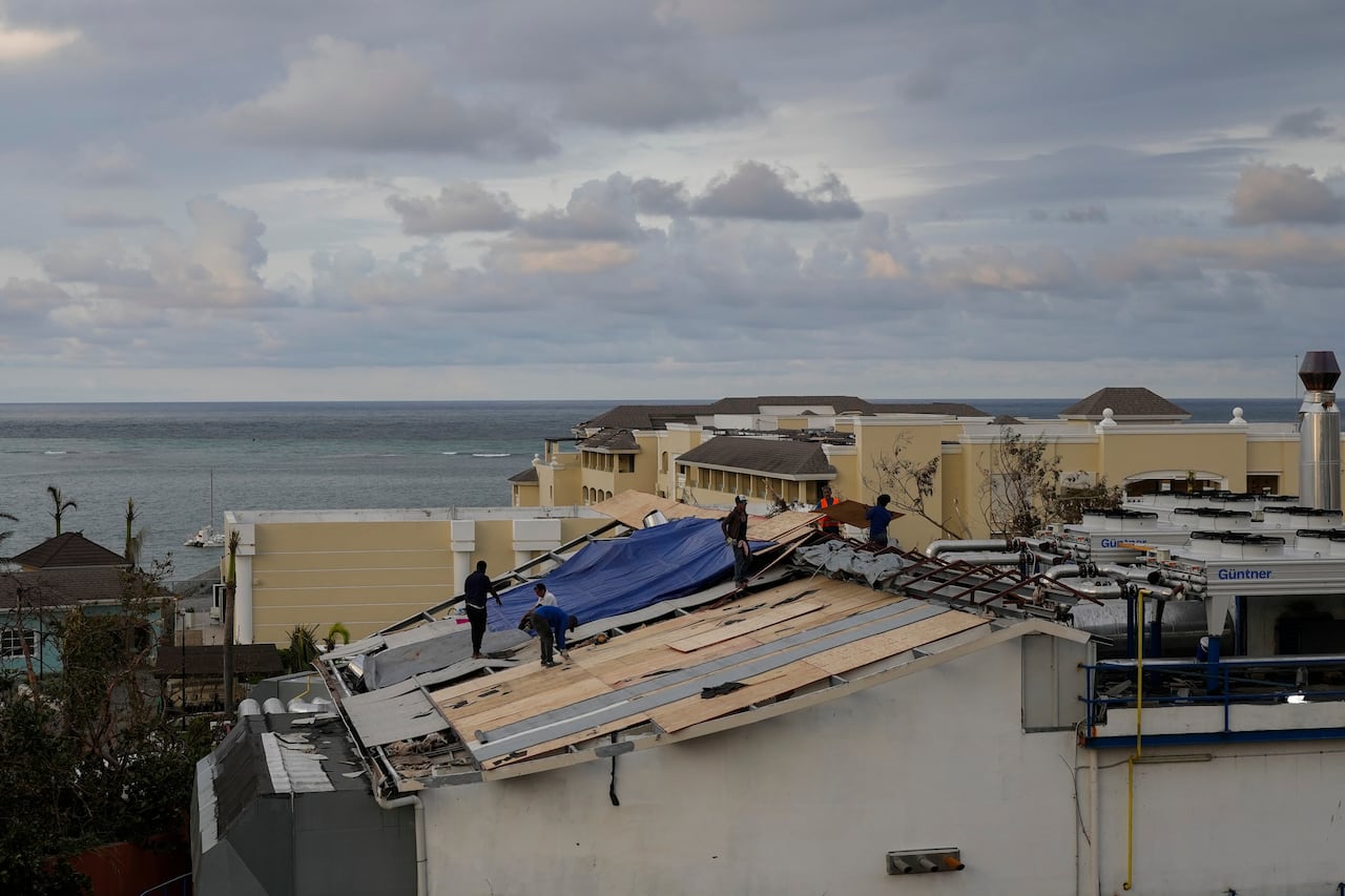 workers on the roof, with blue tarup and wooden slats