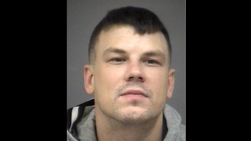 Head shot of a white man in his 30s in a grey hoodie against a grey background