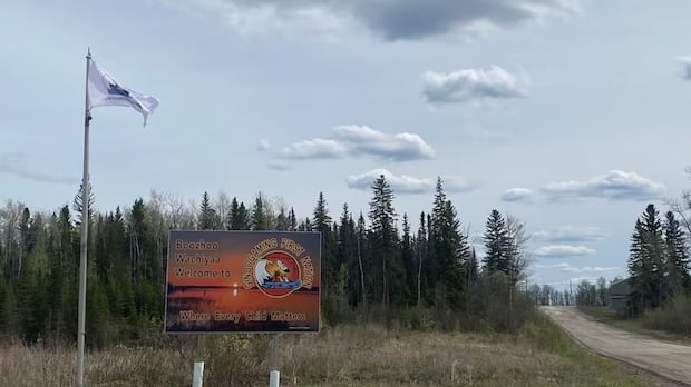 A sign next to a road welcomes people to Ginoogaming First Nation