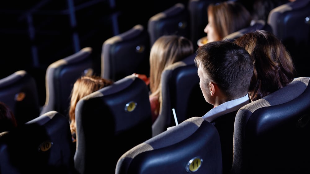 People facing distant  from camera successful  movie   theatre seats