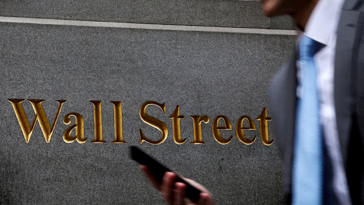 a antheral   walks past   the golden  engraved lettering connected  the broadside  of a gathering  that reads 'Wall street"