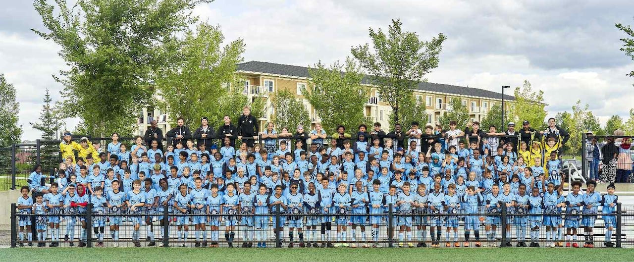 A hundred or so Elite players and coaches pose on field for group shot