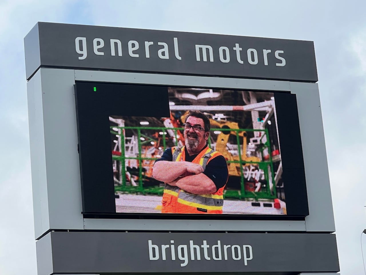 A billboard sign shows an auto worker on the job.