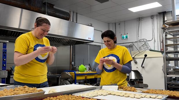 Two women make perogies in a commercial kitchen. Two Ukrainian women make perogies in a commercial kitchen.