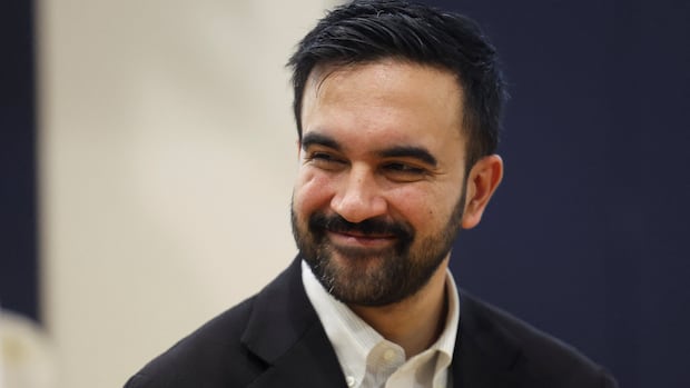 man with dark hair and facial hair smiling