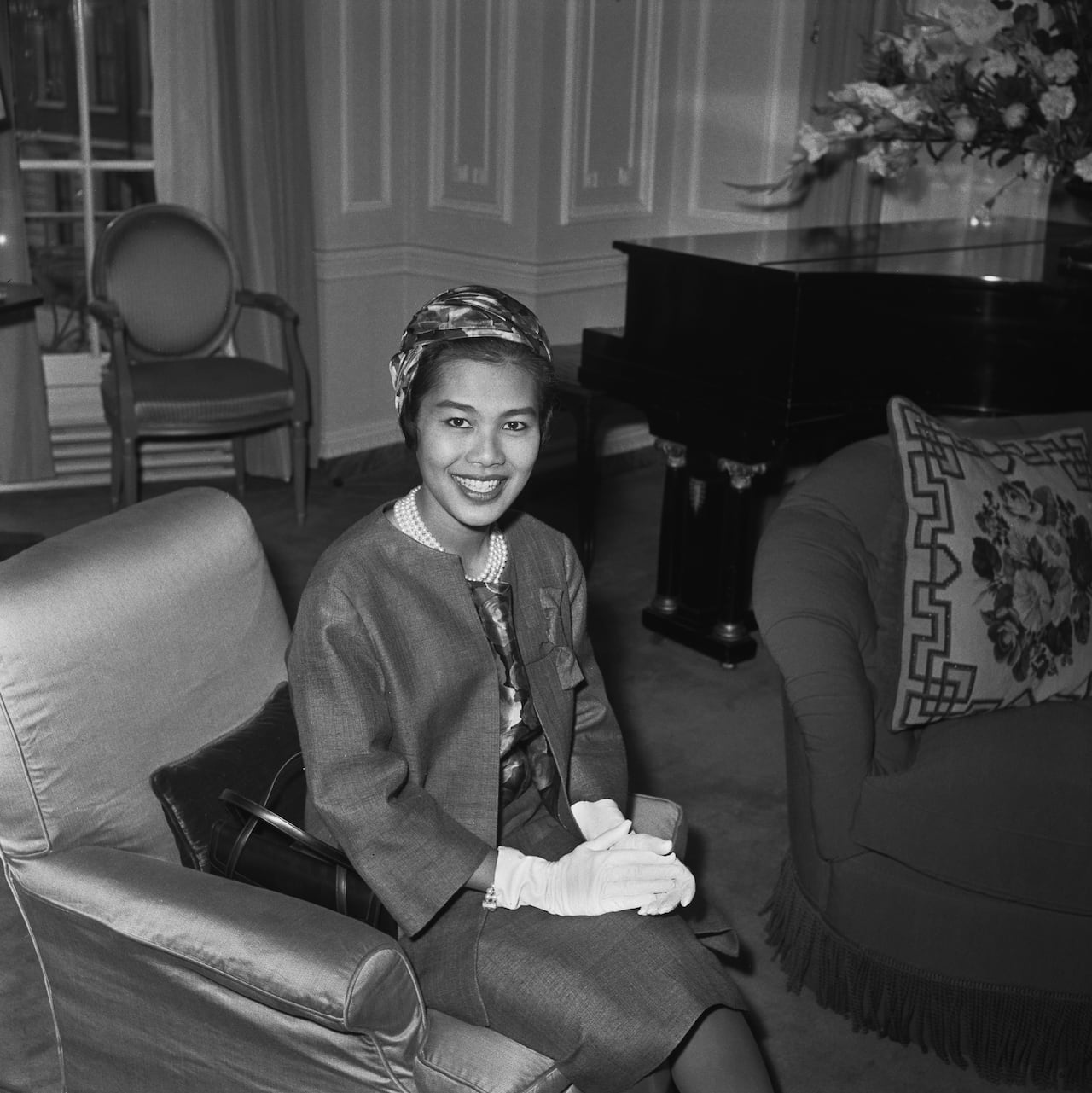 A person sits and smiles while posing for a photograph in this black and white image.