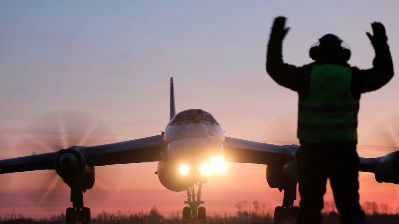 Person stands in front of an aircraft with arms raised