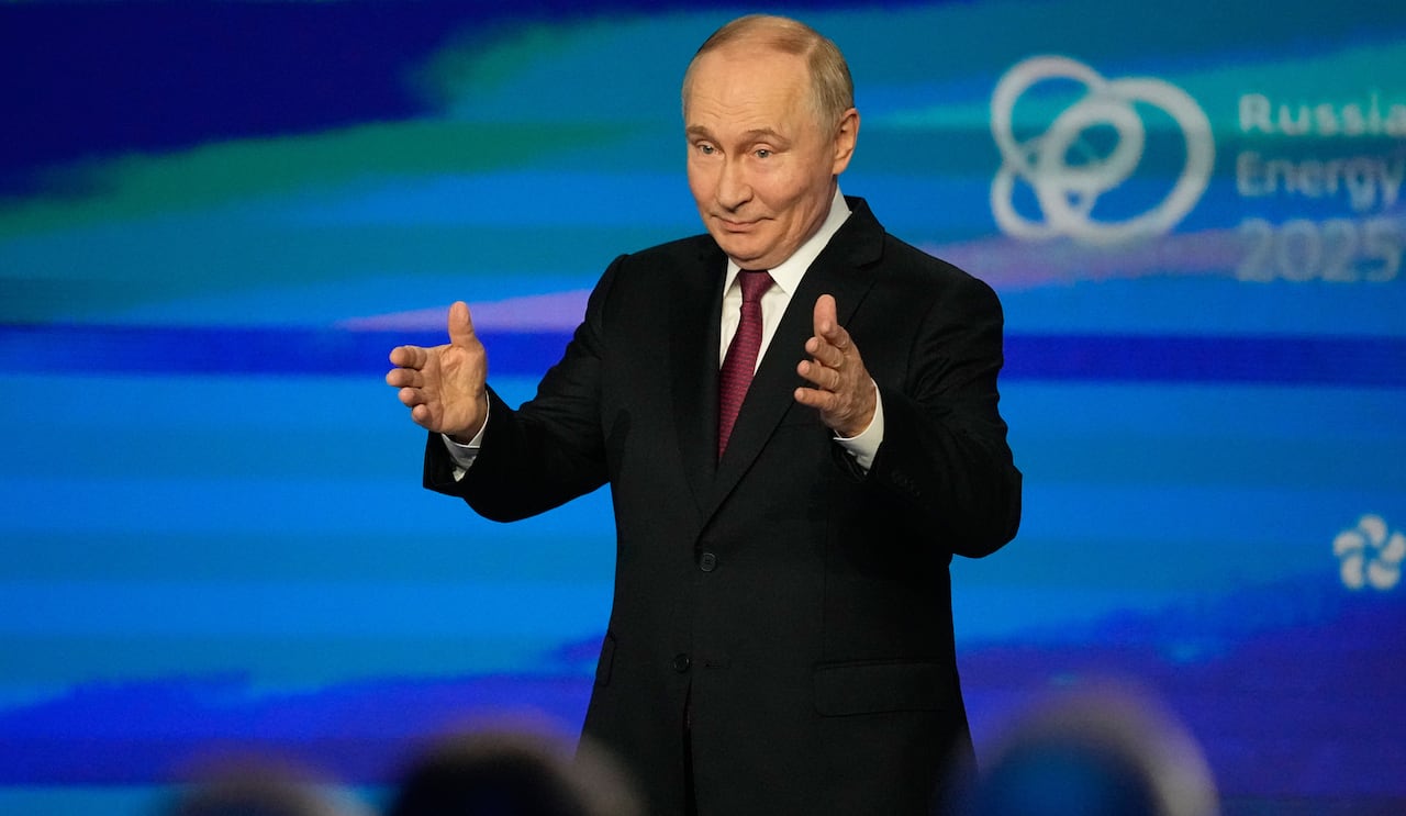 Putin, wearing a dark suit, stands in front of a blue screen with the words Russia Energy 2025. 