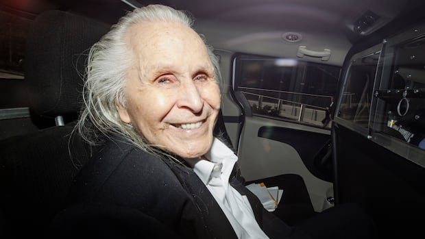 A man wearing a black blazer and a white t-shirt is smiling to the camera.