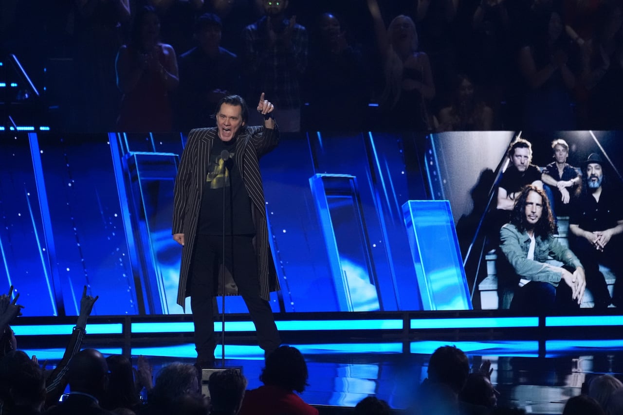 Jim Carrey, seyircilere konuşurken heyecanla mavi ışıklı bir sahnede duruyor